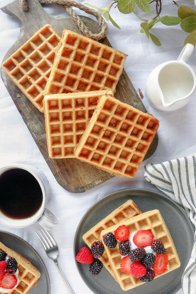 Belgian Spelt Waffles arranged on a wood cutting board.