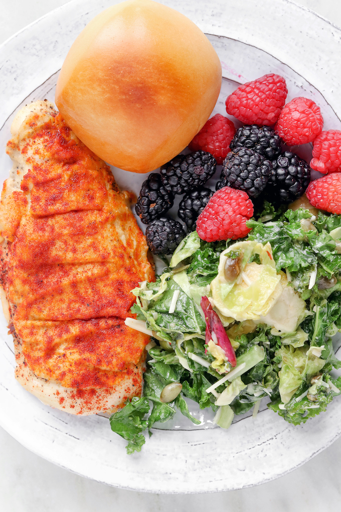 3-Ingredient Hummus Crusted Chicken on a white plate with brussel slaw and fresh berries.