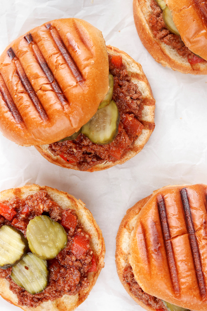 Whole Food Sloppy Joes topped with pickles. They are sitting on top of white parchment paper.
