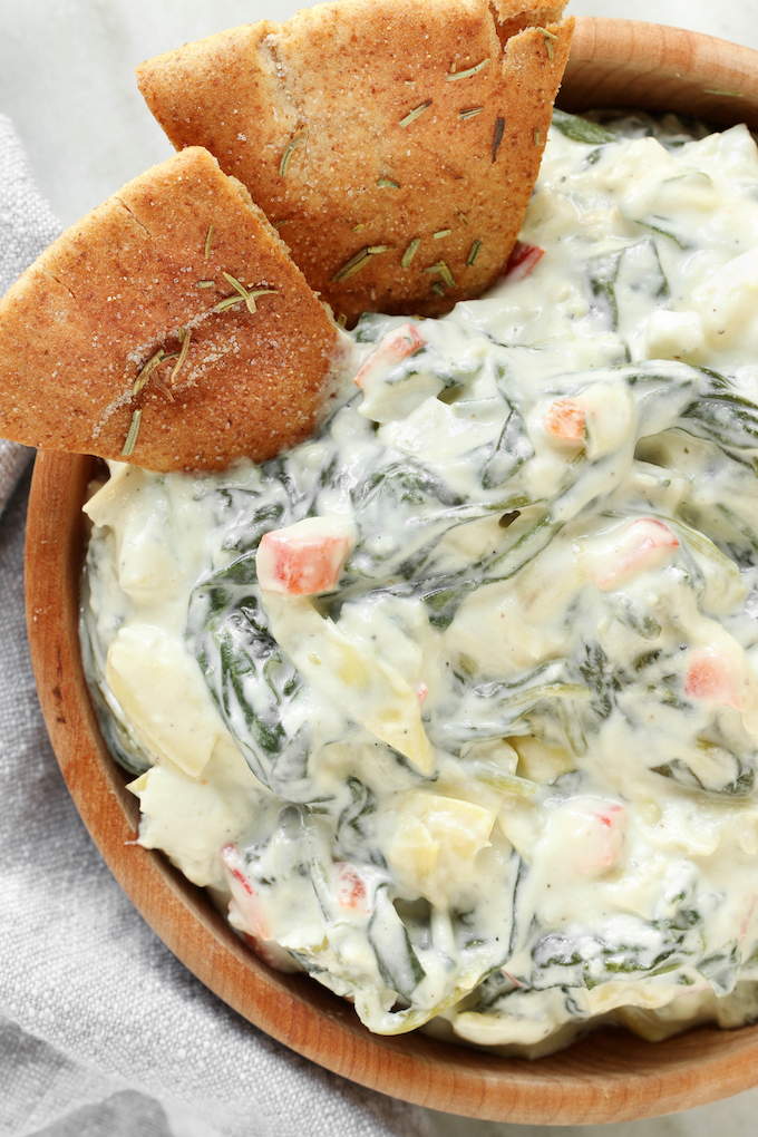 Slow Cooker Spinach Artichoke Dip in a wooden bowl sitting on a white marble counter.
