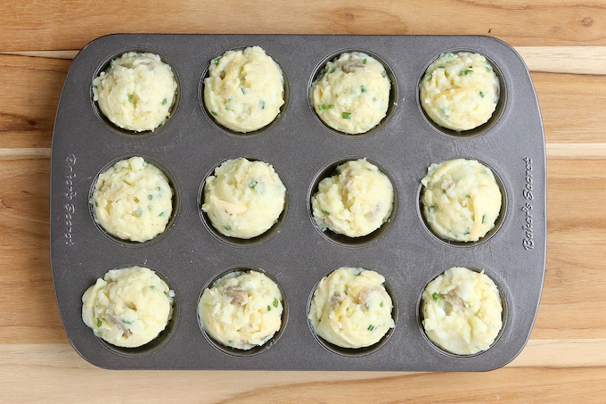 Leftover mashed potato puffs ready for the oven. Batter is divided among the cups of a mini muffin pan.