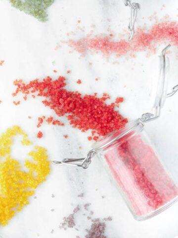 Homemade sprinkles spilling from jars on a white countertop.