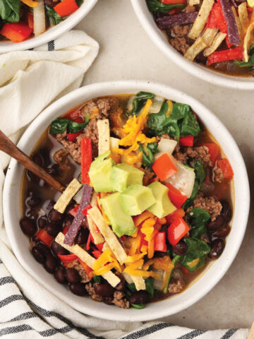Vegetable Taco Soup topped with garnishes in white bowls.
