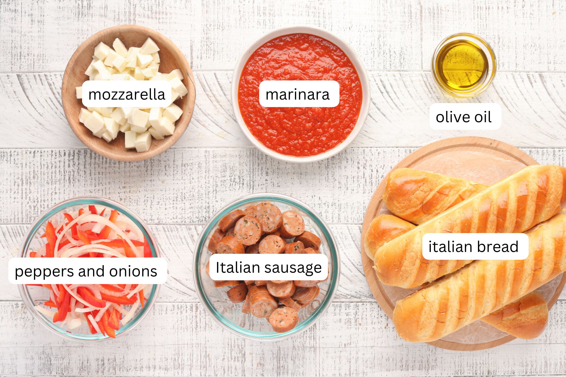 Italian sausage on a bun ingredients - marinara, sausage, mozzarella, olive oil, peppers, onions and Italian bread.