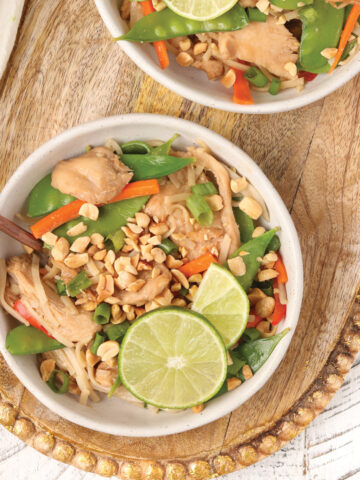 Healthy Chicken Pad Thai topped with peanuts, green onions, limes and cilantro.