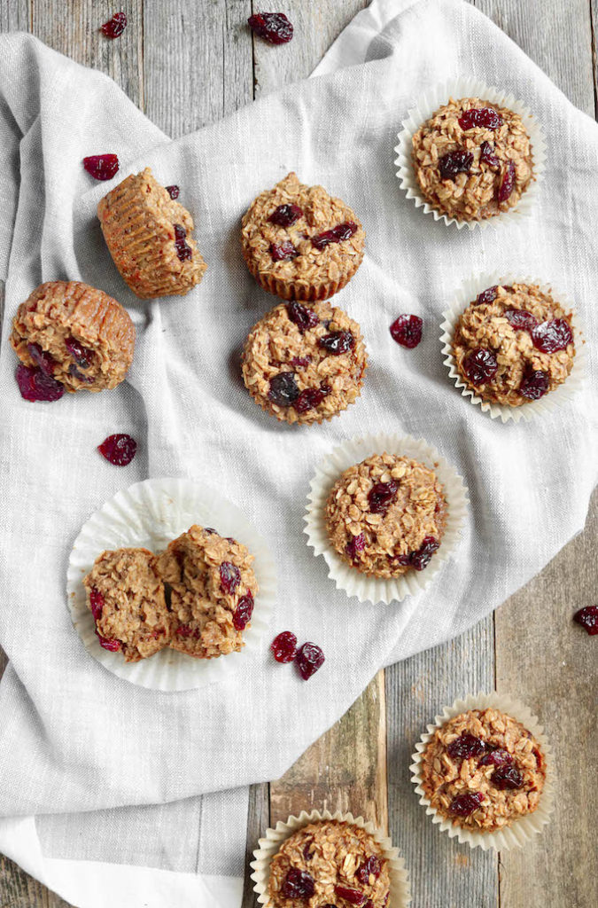 Cherry + Vanilla Baked Oatmeal Cups arranged on a gray napkin. Background is distressed wood.