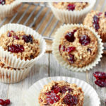Cherry + Vanilla Baked Oatmeal Cups arranged sporadically on a baking rack and on a wooden surface.