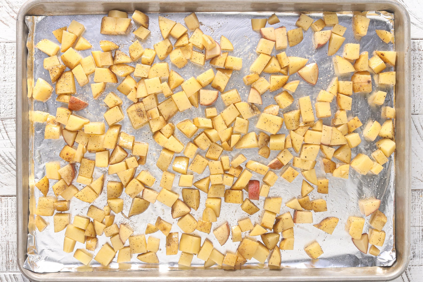 Diced Yukon gold potatoes spread across a sheet pan before roasting.