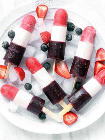 Red White and Blue Bomb Pops on a white plate filled with ice.