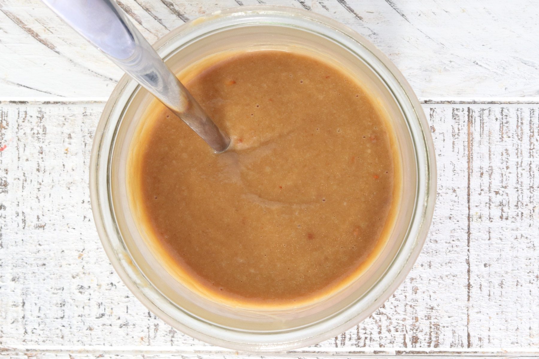 Thai peanut dressing made with peanut butter, lime juice, soy sauce, garlic, and ginger in a glass jar.