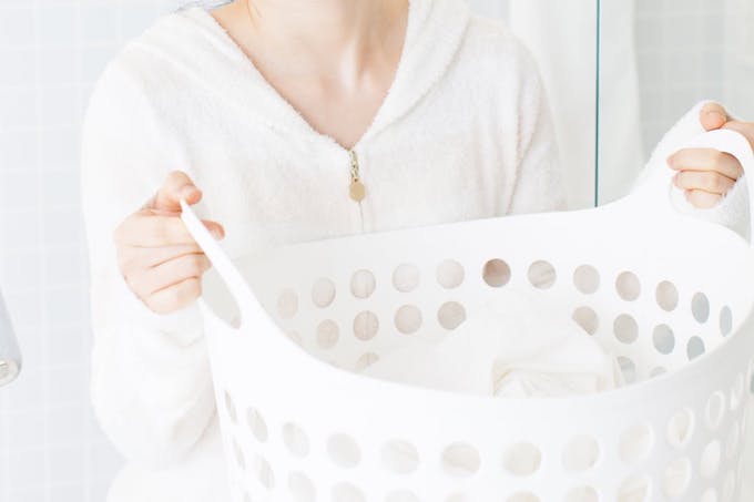 Woman holding white laundry basket filled with white socks.