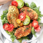 Easy Oven-Baked Parmesan Chicken on a platter with red and green tomatoes.