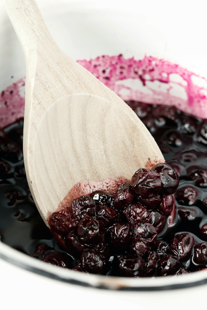 Homemade Blueberry Syrup bubbling in a white sauce pan.