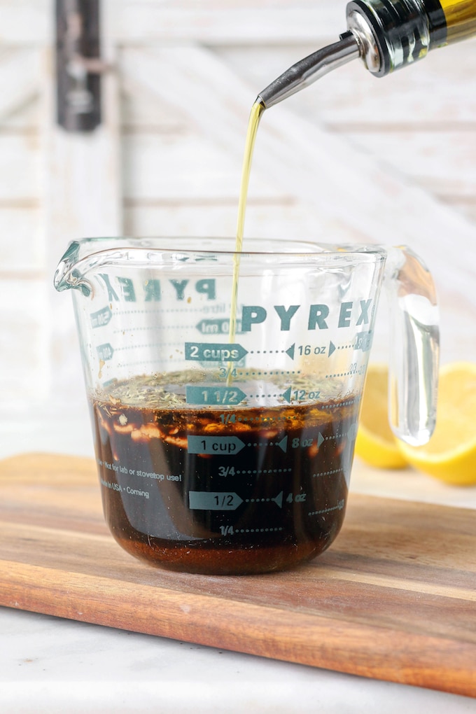 Simple Spiced Balsamic Chicken Marinade in a glass Pyrex measuring Dish. Olive oil is being poured from the upper right and hand corner.