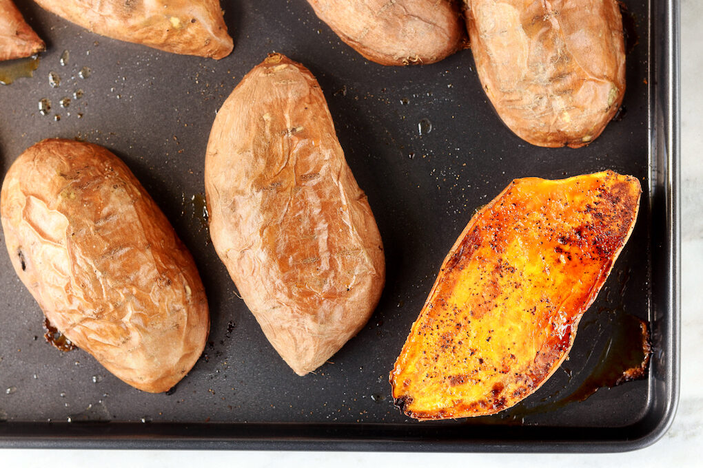 Step 1: Loaded Baked Mexican Sweet Potatoes. Carmalized sweet potatoes on a black sheet pan.