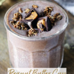 Peanut Butter Cup Protein Smoothie in a glass cup. It is garnished with granola and peanut butter cups.