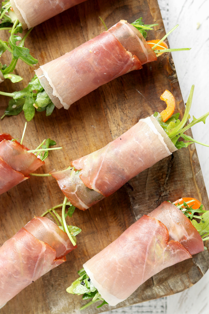 Prosciutto Arugula Salad Wraps displayed in 2 rows on a wooden cutting board.