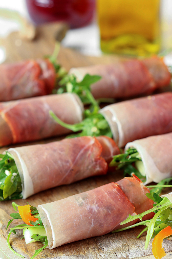 Prosciutto Arugula Salad Wraps displayed in 2 rows on a wooden cutting board.