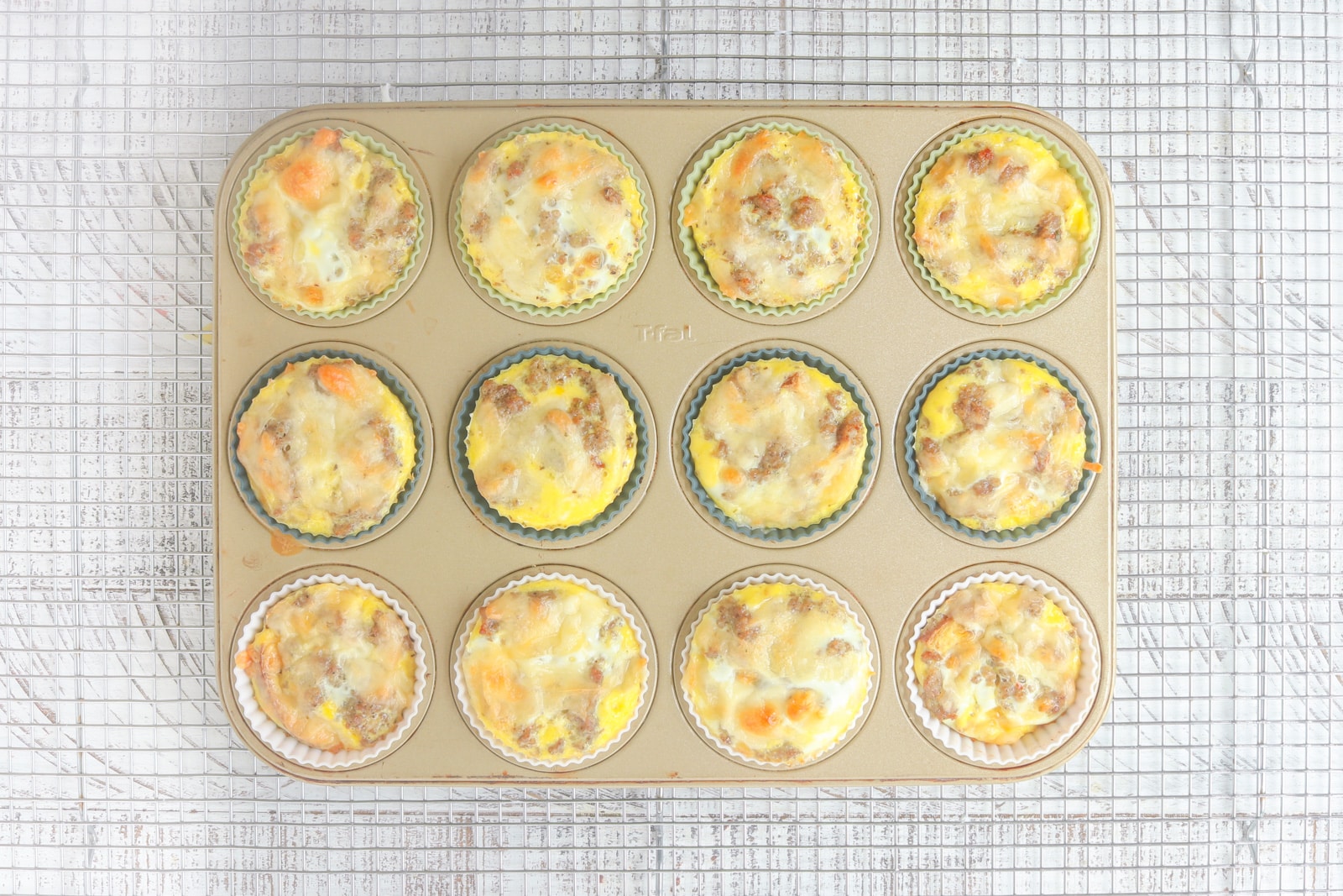 Freezer Friendly Baked egg muffins cooling in a gold muffin pan. 