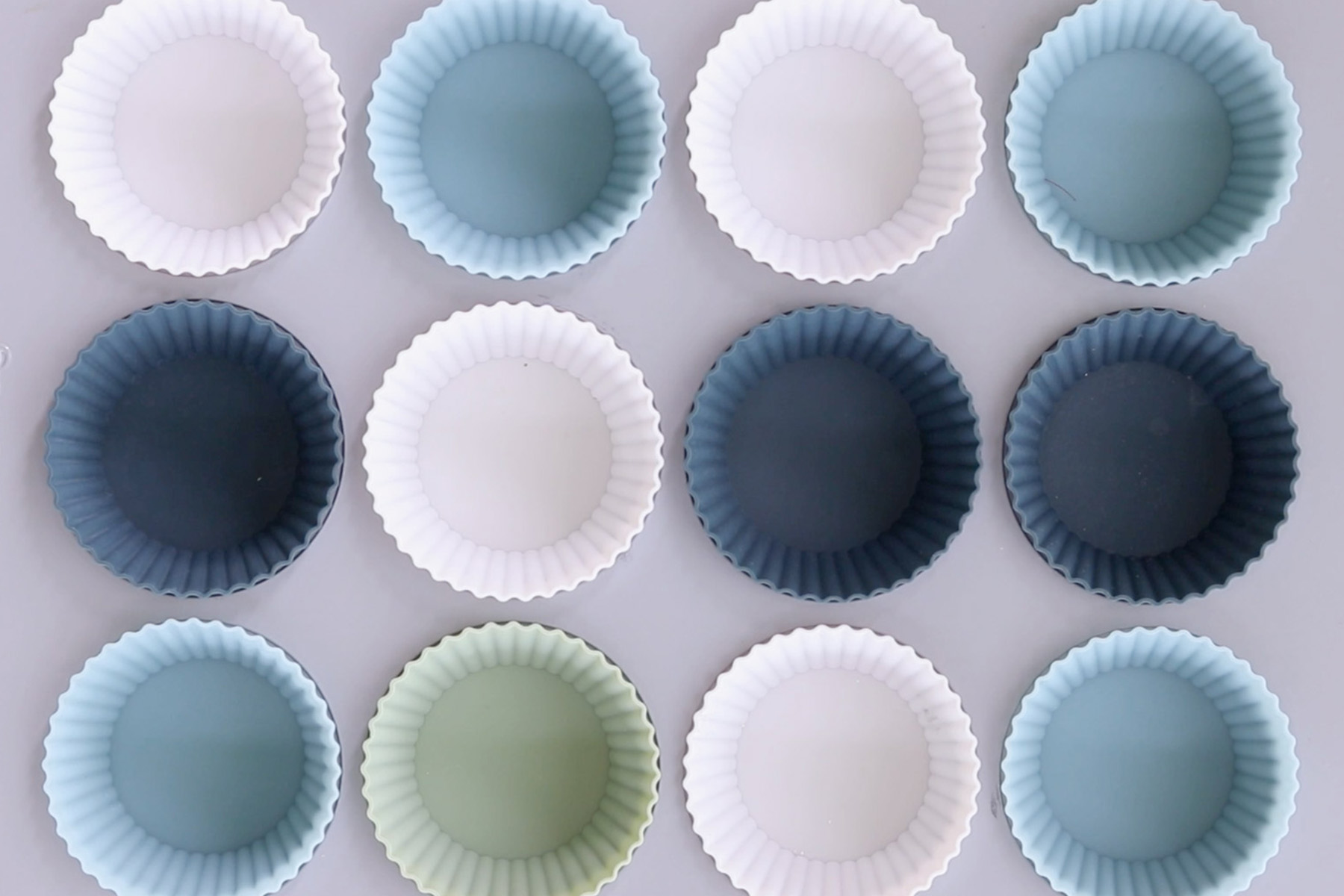 Individual silicone muffin liners arranged inside a regular 12-cup muffin pan.