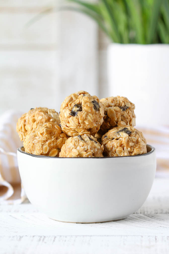 No Bake Peanut Butter Power Balls arranged in a white bowl with a yellow and white striped napkin in the background.