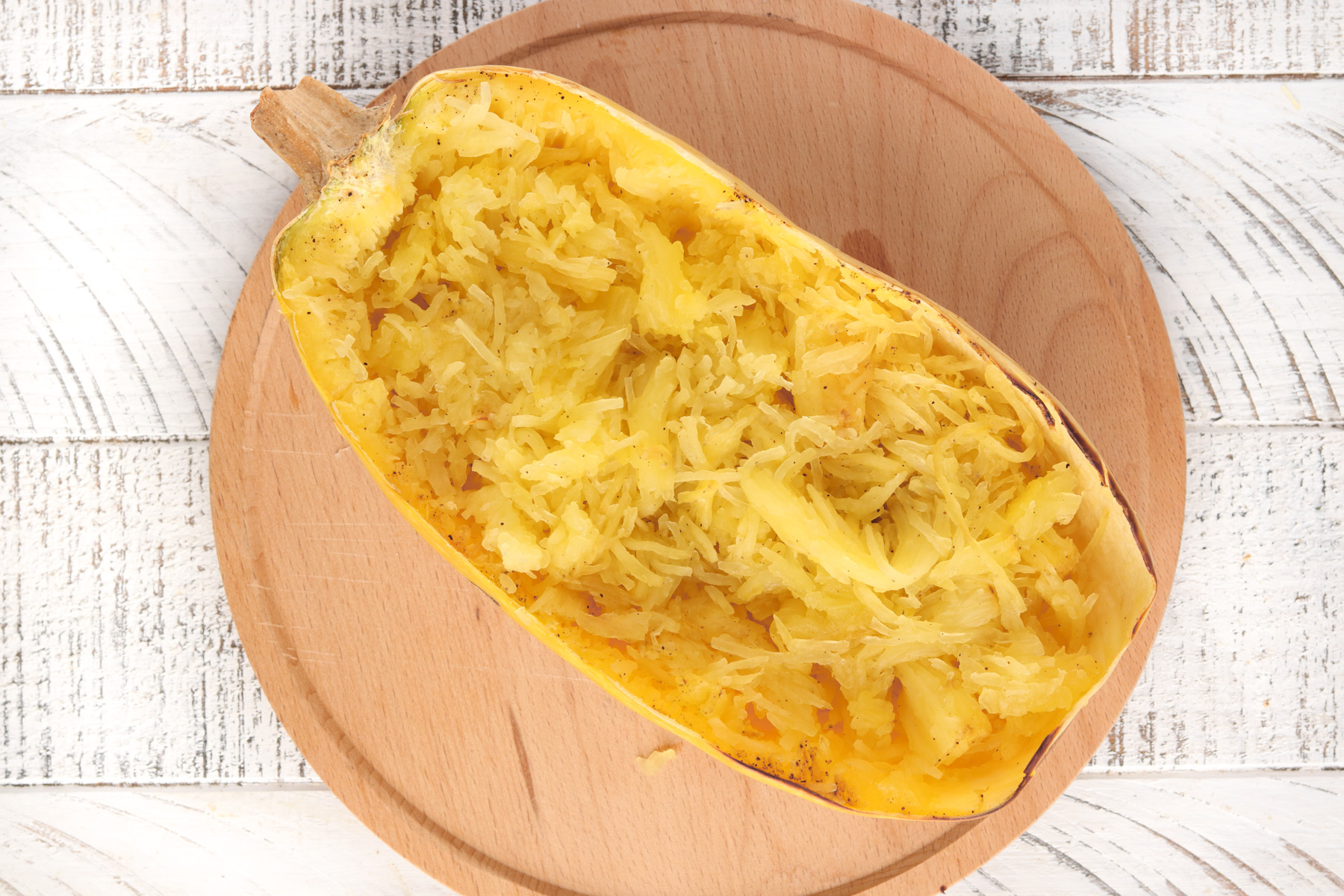 Spaghetti squash sliced in half and shredded with a fork. 