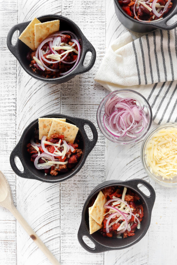 Easy Instant Pot Turkey Chili arranged in small black bowls on a wooden surface.
