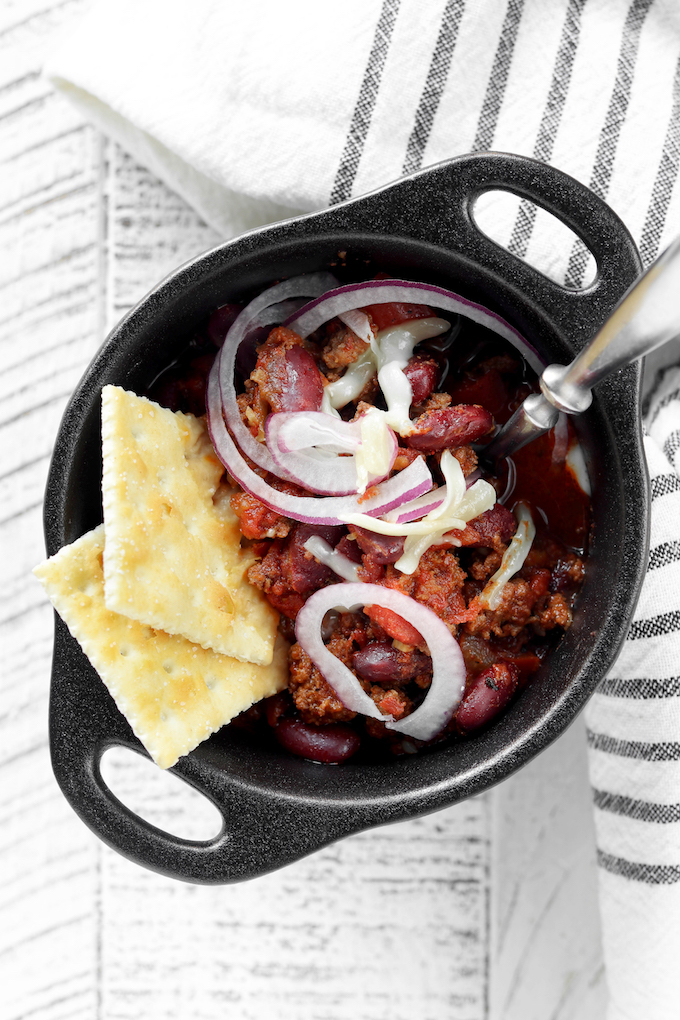 Easy Instant Pot Turkey Chili garnished with onions, cheese and 2 saltine crackers.