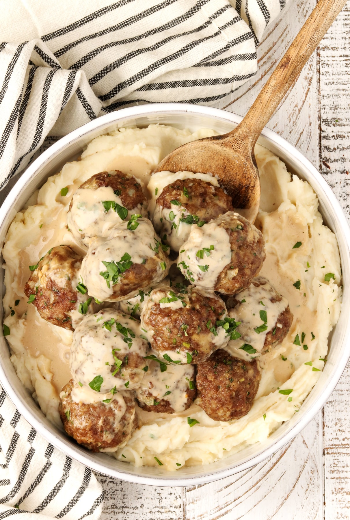 Instant Pot Swedish Meatballs piled into a large white bowl of mashed potatoes.