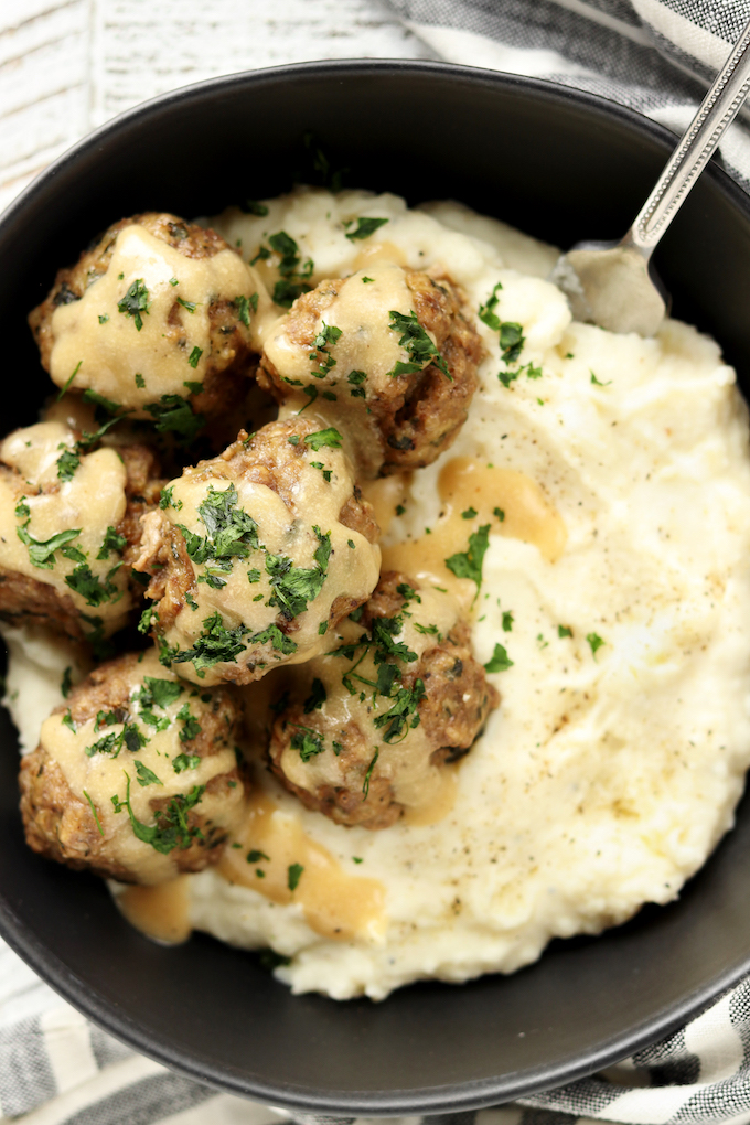 Close up view of Instant Pot Swedish Meatballs and Mashed Potatoes in a plain black bowl.