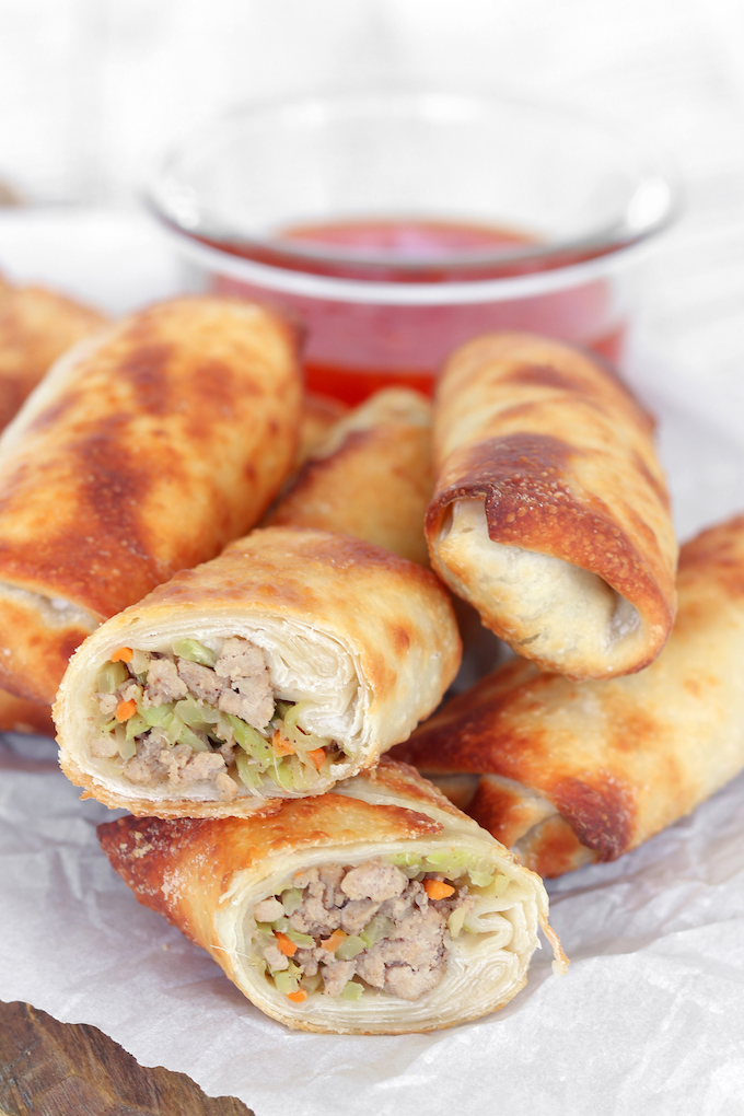 Healthier Air Fryer Egg Rolls  stuffed with turkey and cabbage arranged on a wooden cutting board.