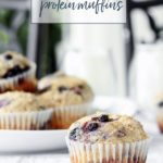 To Die For Blueberry Protein Muffins arranged on a table with milk.