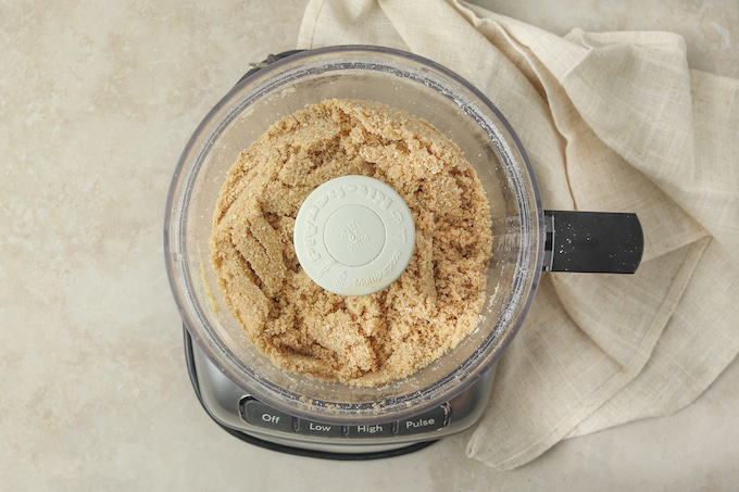 Food processor filled with the pulsed oats, almonds, salt, butter and coconut sugar. 