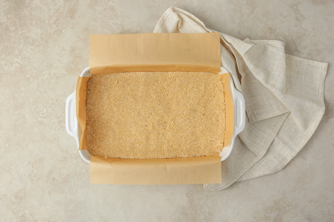 A rectangle baking dish filled with almond and oat crust.