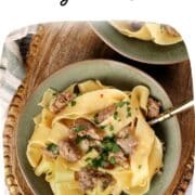 Bowl of 20-minute sausage carbonara made with wide pappardelle noodles, browned Italian sausage, and fresh parsley, served in a green bowl on a wooden tray.