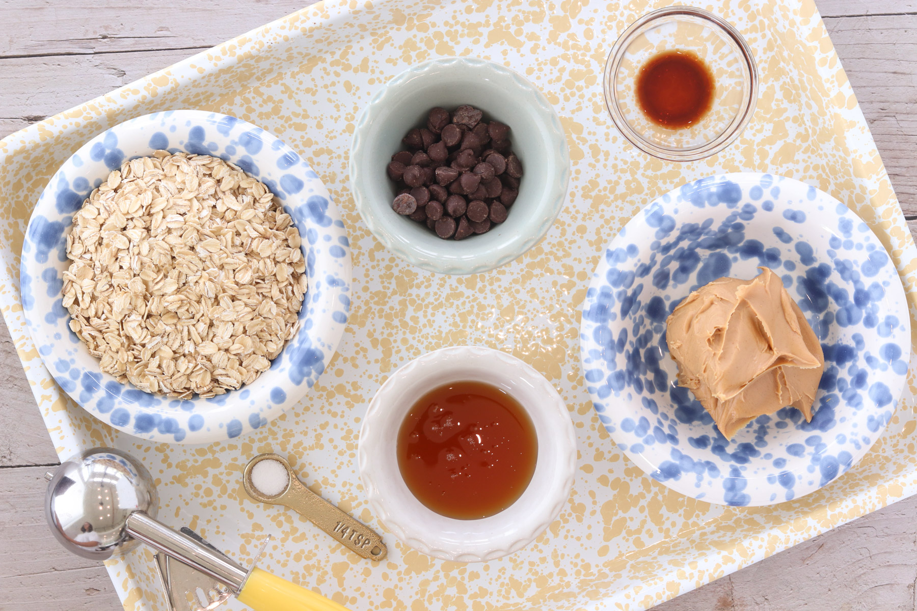 Ingredients for no-bake peanut butter power balls, including oats, chocolate chips, peanut butter, honey, vanilla and salt, arranged on a tray.