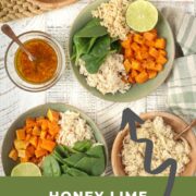 Honey Lime Chicken Macro Bowls on a white table surrounded by brown rice, sweet potatoes, dressing and chicken.