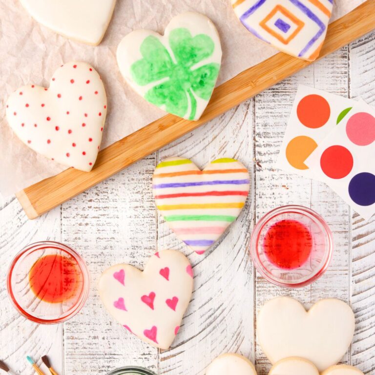 Overhead view of a table with paint your own cookie supplies and decorated painted heart cookies.