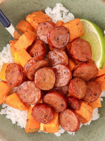 Honey-lime chicken sausage bowl with roasted sweet potatoes, white rice and lime wedges, served with honey-lime dressing.