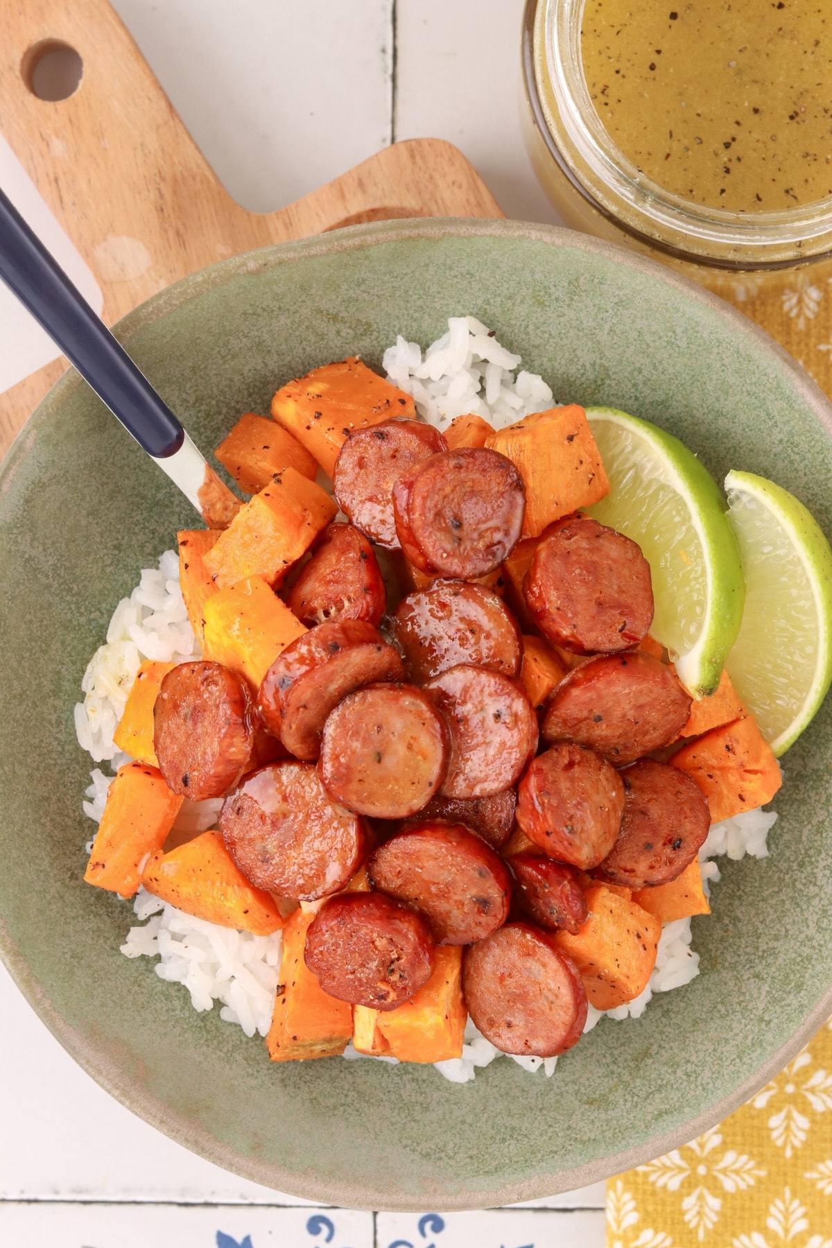 Honey-lime chicken sausage bowl with roasted sweet potatoes, white rice and lime wedges, served with honey-lime dressing.