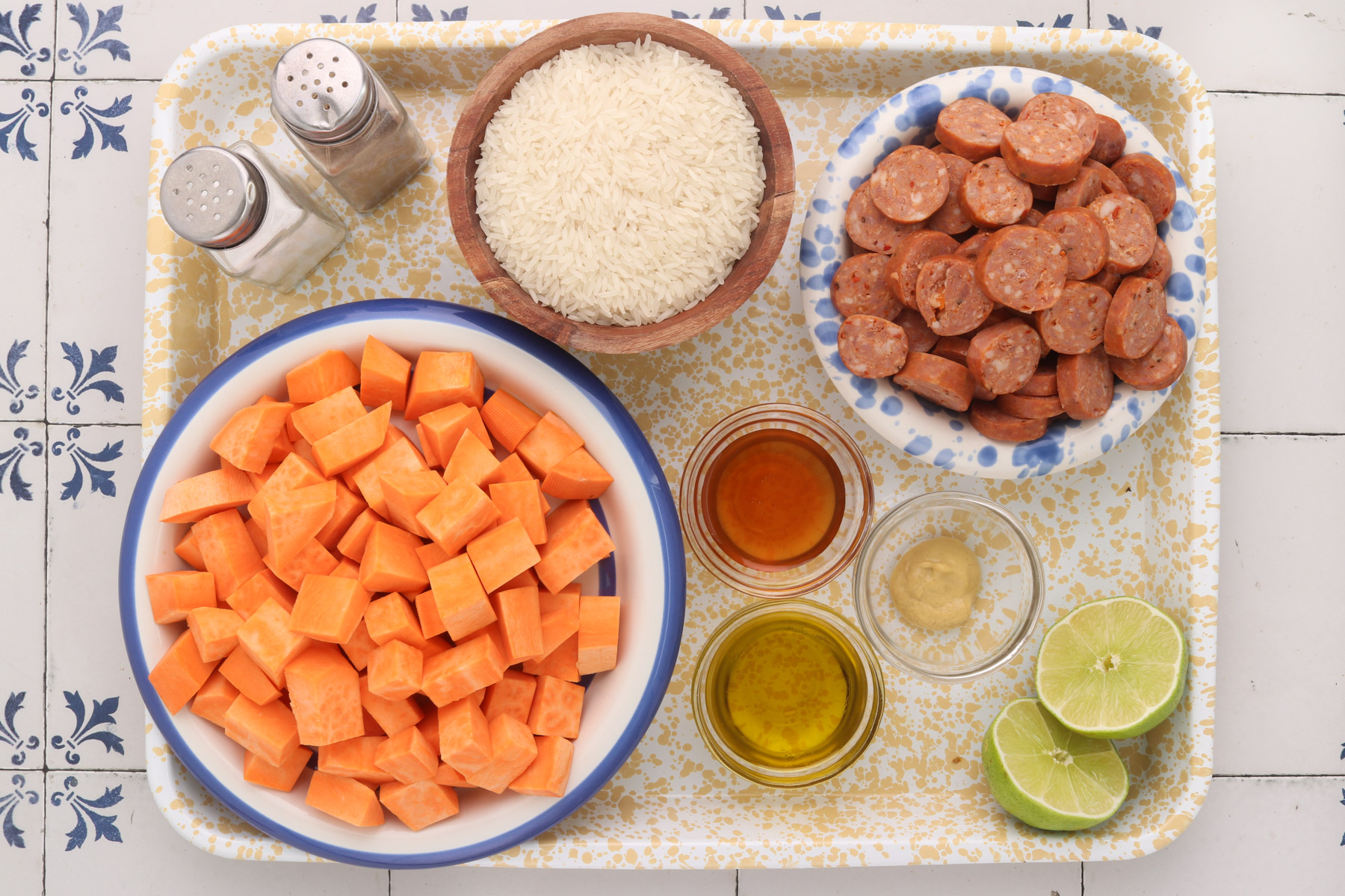 Ingredients for honey-lime chicken sausage bowls: cubed sweet potatoes, sliced chicken sausage, white rice, avocado oil, honey, Dijon mustard, limes, salt and pepper.