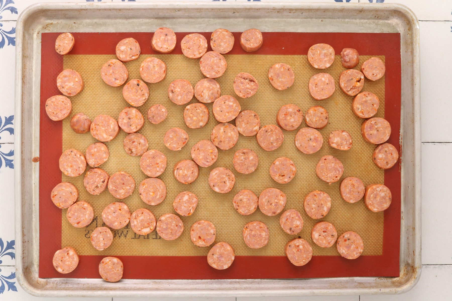 Sliced fully cooked chicken sausage arranged in a single layer on a parchment-lined sheet pan before roasting.