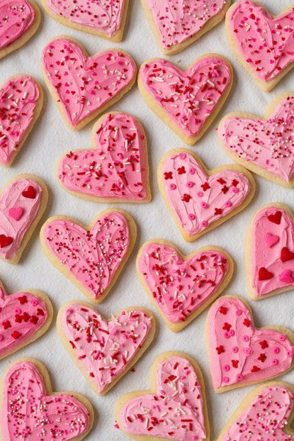 Heart shaped sour cream cookies decorated with pink icing and red sprinkles.
