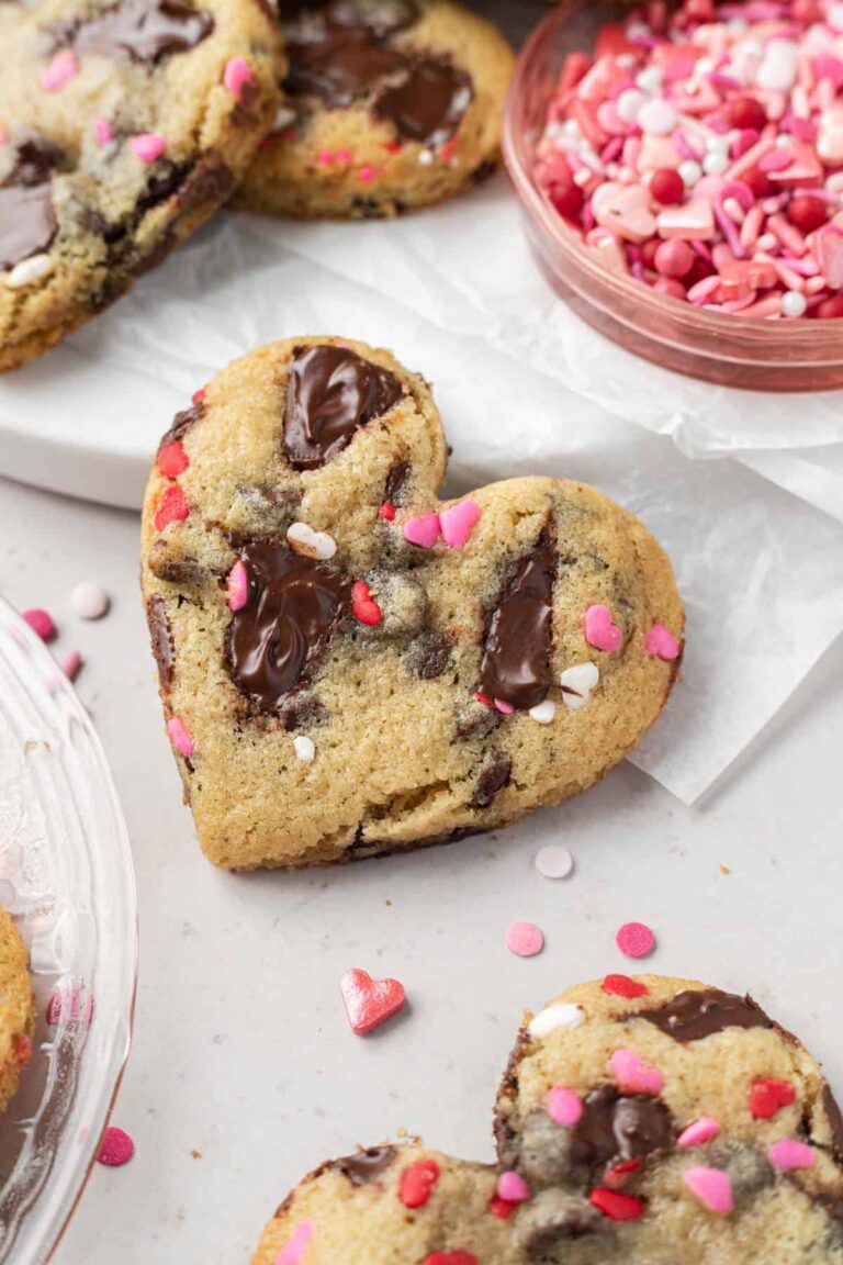 Heart shaped chocolate chip cookies with pink and white sprinkles ready for a classroom party.