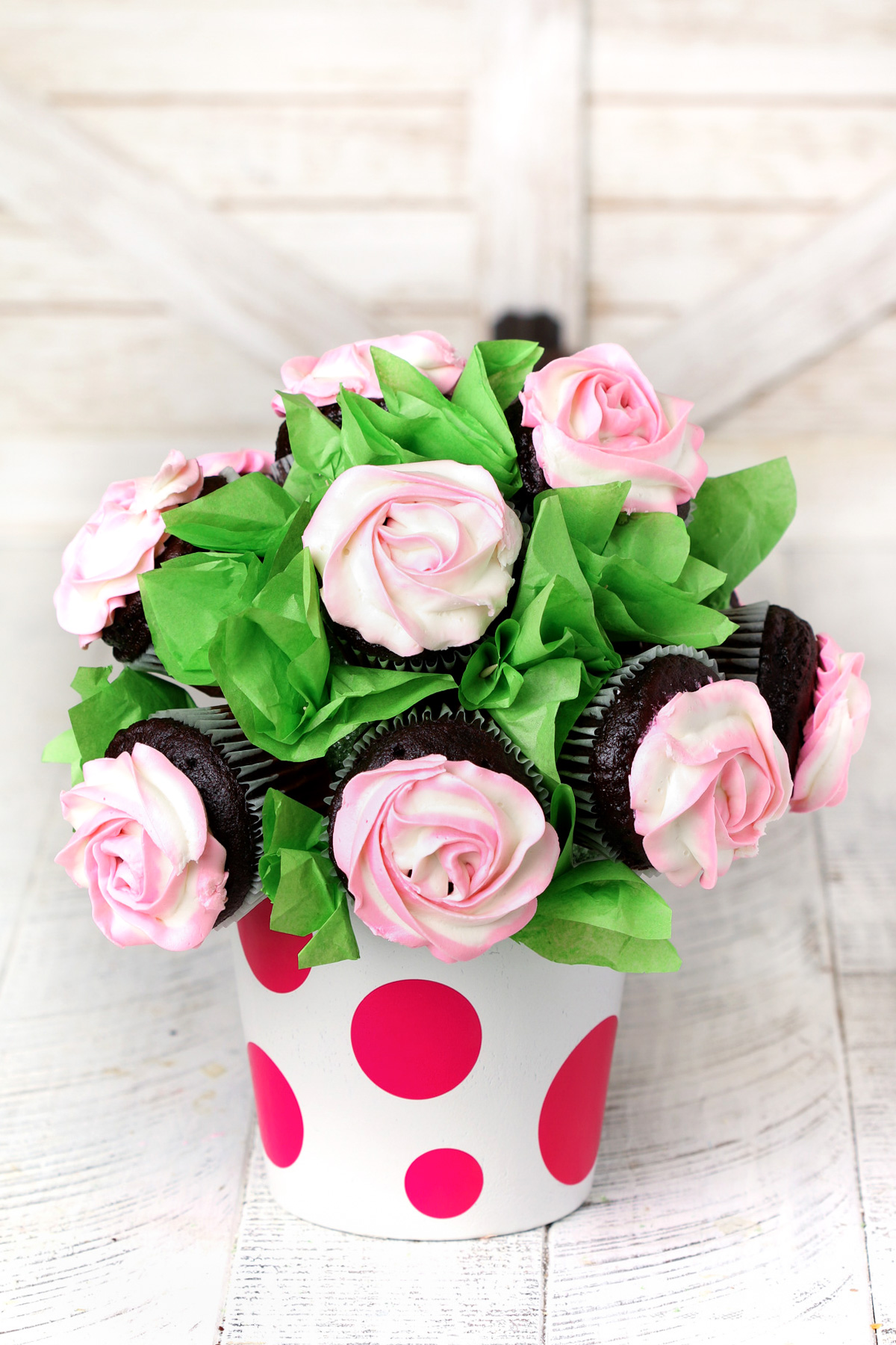 Pink rose cupcake bouquet in a white pot with pink polka dots.