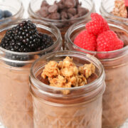 Chocolate Blended Overnight Oats in mason jars with various toppings - berries, granola and chocolate chips.