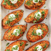 Loaded Mexican sweet potatoes stuffed with ground beef, black beans, corn, and cheese, topped with sour cream and cilantro.