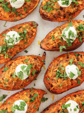 Loaded Mexican sweet potatoes stuffed with ground beef, black beans, corn, and cheese, topped with sour cream and cilantro.