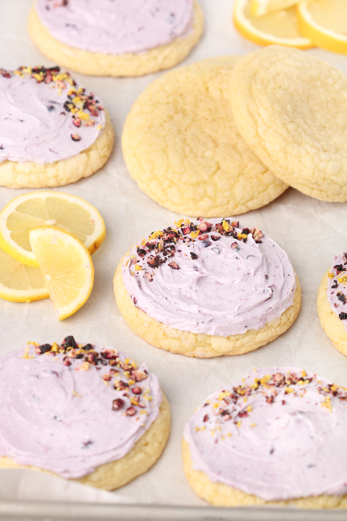 Lemon Blueberry Cookies on a sheet pan with lemons and fresh blueberries.