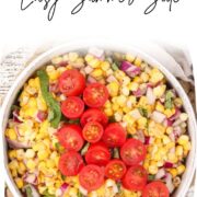 Easy Corn Salad in a white bowl and garnished with basil and cherry tomatoes.